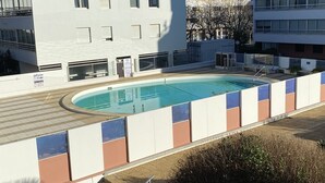 A modern building with a swimming pool, a staircase, and a view of other buildings. - Charming studio with pool - 2 guests (La Grande-Motte)