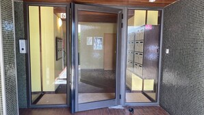 A hotel entrance with a glass door, tiled walls, and a wooden ceiling. - Charming studio with pool - 2 guests (La Grande-Motte)