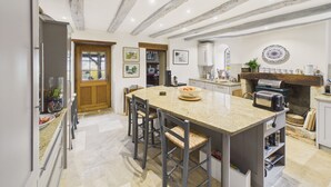 A kitchen with a central island, wooden beams on the ceiling, and a stone backsplash. - Typical Dordogne house with pool & views (Urval)