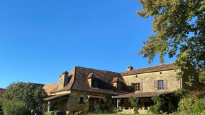 A stone building with a tiled roof, a covered porch, and a grassy lawn. - Typical Dordogne house with pool & views (Urval)