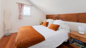 Un dormitorio con cabecera de madera, ropa de cama blanca y una manta marrón.