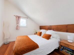 Ein Schlafzimmer mit einem hölzernen Kopfteil, weißer Bettwäsche und einer braunen Tagesdecke.