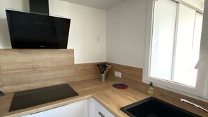 Una cocina moderna con estufa integrada, una ventana y un lavamanos.