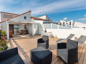 Eine Dachterrasse mit Sitzgelegenheiten im Freien und einer Schiebetür zu einem Innenraum.