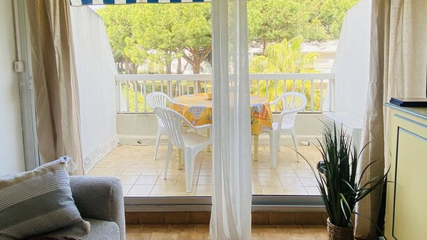 Ein Balkon mit weißen Stühlen und einem Tisch, einer Couch und einem Blumentopf.