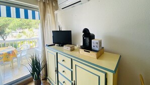 Ein Zimmer mit Fernseher, Kaffeemaschine und einem kleinen Schrank.