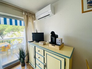Ein Zimmer mit Fernseher, Kaffeemaschine und einem kleinen Schrank.