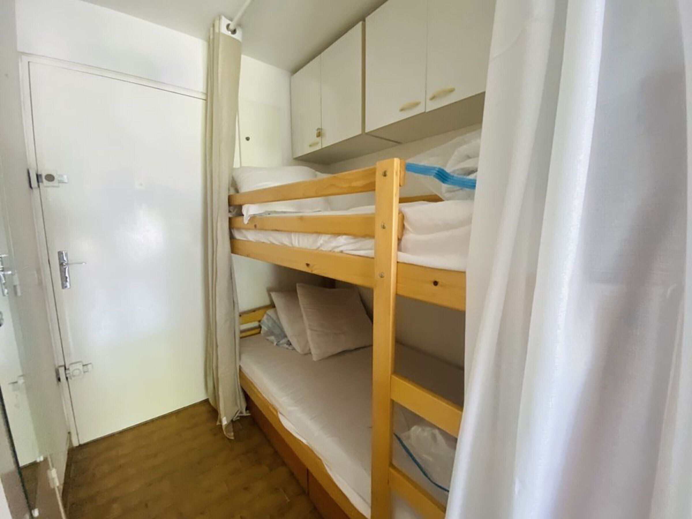 Une chambre avec un lit superposé, une armoire et une porte.