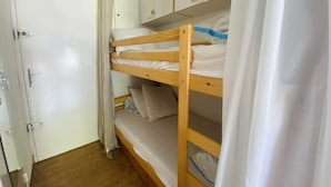 Ein Schlafraum mit Etagenbetten, einem Kleiderschrank und einer Tür.