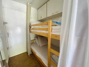 Ein Schlafraum mit Etagenbetten, einem Kleiderschrank und einer Tür.
