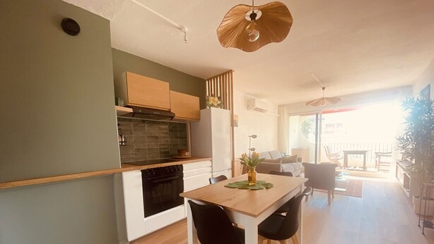Une cuisine moderne avec un coin repas, un plancher en bois et une vue sur l’extérieur.