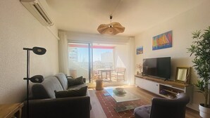 Un salon avec un canapé, un fauteuil, une télévision et un balcon offrant une vue agréable.