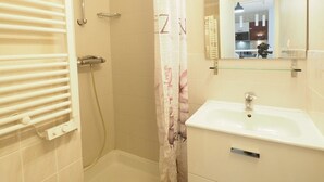 Un bagno con doccia, lavandino, specchio e portasciugamani.