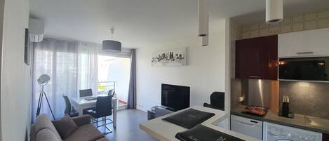 Un apartamento moderno con sala de estar, comedor, kitchenette y vistas a la ciudad.