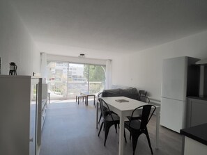 Een moderne keuken met een eethoek, grote ramen en uitzicht op gebouwen.
