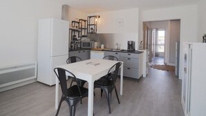 Cocina compacta con comedor, electrodomésticos blancos y diseño moderno.