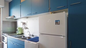 Eine Küche mit blauen Schränken, einem weißen Kühlschrank und einer Kaffeemaschine.