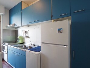 A kitchen with blue cabinets, a white refrigerator, and a coffee maker. - Sea view apartment, AC, parking - 6 guests (La Grande-Motte)