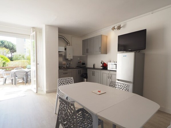 A modern kitchen with white cabinets, a built-in microwave, and a flat-screen TV. - Cozy studio, pets welcome, parking - 4 guests (La Grande-Motte)