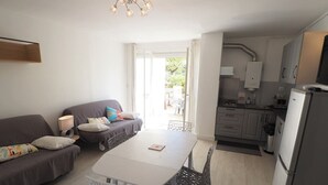 Ett kompakt bostadsutrymme med en soffa, ett bord, stolar, ett köksområde och ett matbord.