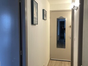 A hallway with a door, a framed sign, and a light fixture. - Renovated apartment with parking - 7 guests (Le Grau-du-Roi)