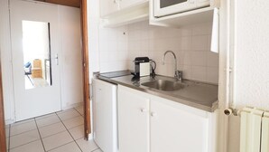 A kitchen with white cabinets, a stainless steel sink, a microwave, and a coffee maker. - Apartment with AC, sea view, parking - 4 guests (La Grande-Motte)