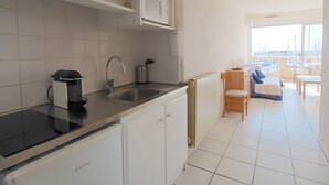 A modern kitchen with a built-in stove, a sink, and a window overlooking a balcony with a view of the marina. - Apartment with AC, sea view, parking - 4 guests (La Grande-Motte)