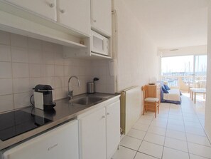 A modern kitchen with a built-in stove, a sink, and a window overlooking a balcony with a view of the marina. - Apartment with AC, sea view, parking - 4 guests (La Grande-Motte)