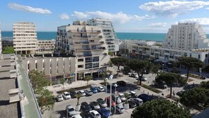 Ett stadsområde vid kusten med moderna byggnader, en parkeringsplats och utsikt över havet.