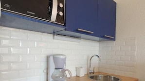 Ett kök med en kaffebryggare, ett handfat och en mikrovågsugn.