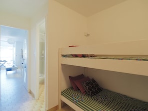 A bunk bed with a patterned bedspread and pillows, a white door, and a visible bathroom with a shower. - Quiet studio with parking - 4 guests (La Grande-Motte)
