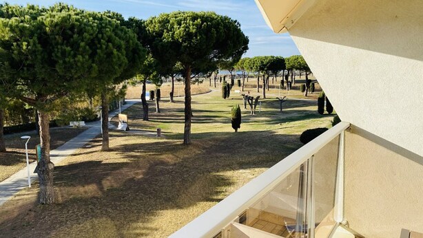 A balcony with a view of a landscaped garden, including trees and a pathway.