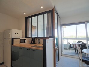 A compact kitchen with a microwave, coffee maker, and a refrigerator. - Apartment with AC, parking - 5 guests (La Grande-Motte)