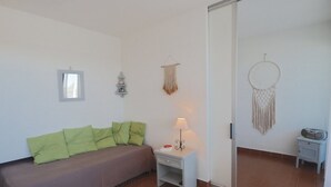 Ein Zimmer mit einem Bett, einem Nachttisch, einer Lampe, einem Wandbild und einer Tür.