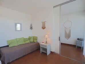 Ein Zimmer mit einem Bett, einem Nachttisch, einer Lampe, einem Wandbild und einer Tür.