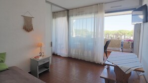 Ein Zimmer mit einem Bett, einem Schreibtisch, einem Sessel, einem Fernseher und einem Balkon mit Blick.