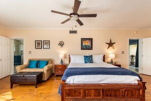 Une chambre à coucher comprenant un lit, un canapé, une table de chevet, un ventilateur de plafond et des éléments de décoration murale.