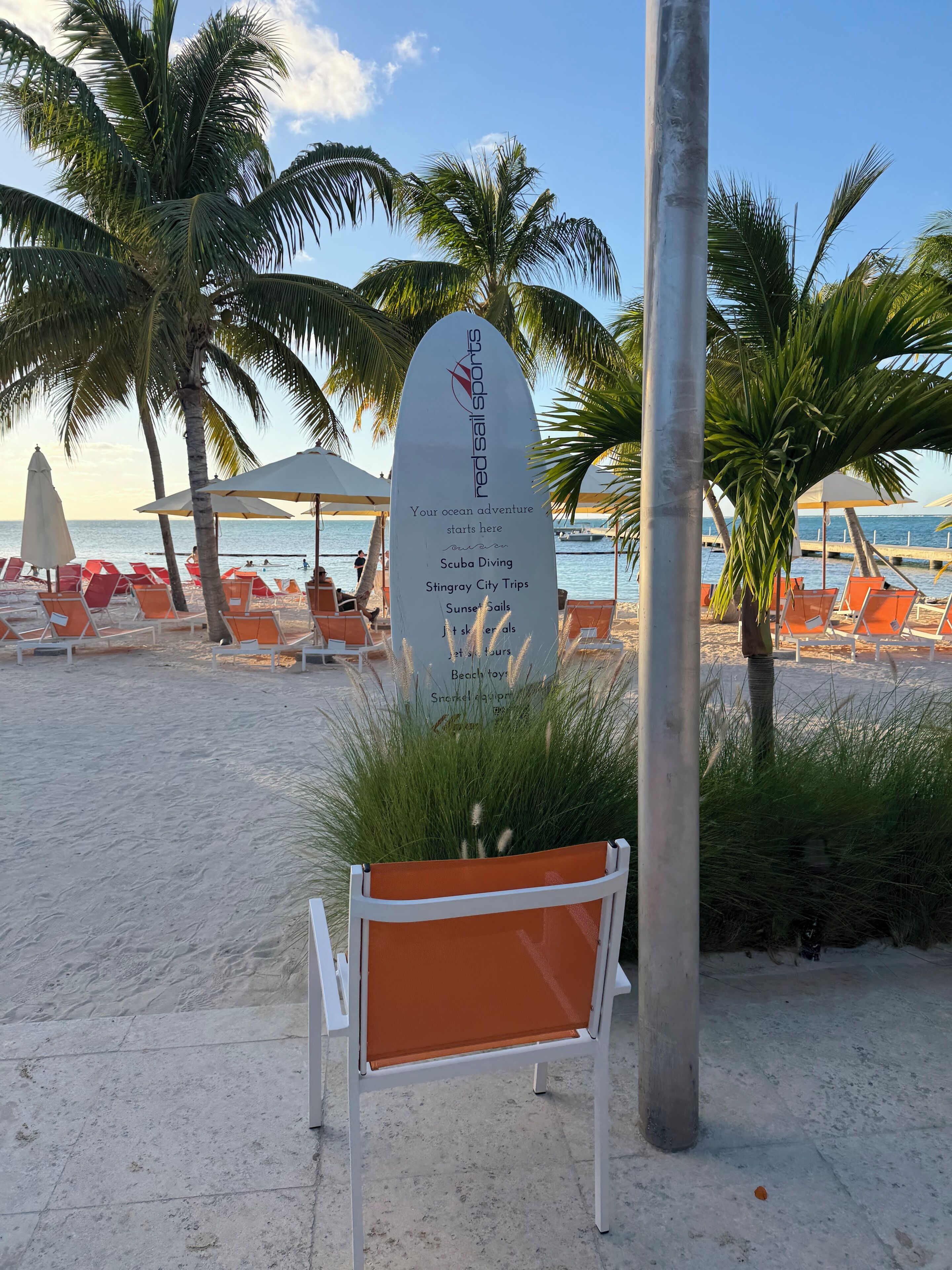 A beachside sign listing activities like scuba diving and stingray city trips.