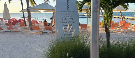 A beachside sign listing activities like scuba diving and stingray city trips.