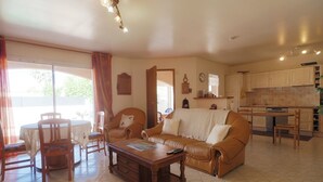 A living room with a sofa, coffee table, and dining area with chairs.
