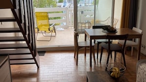 Ein Balkon mit Esstisch, Stühlen und einem gelben Sessel.