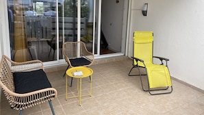 Ein Balkon mit Korbstühlen, einem gelben Tisch und einem gelben Klappstuhl.