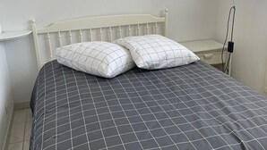 A bed with a checkered bedspread and two pillows, a bedside table, and a lamp. - Lovely apartment, terrace open view - 4 guests (La Grande-Motte)
