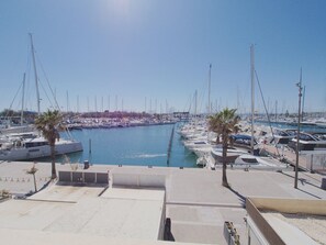 Ein Yachthafen mit vertäuten Booten, wolkenlosem Himmel und ruhiger Wasserfläche.