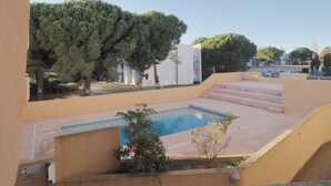 En swimmingpool med trappsteg som leder upp till den, omgiven av träd och byggnader.