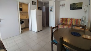 Ett kompakt bostadsutrymme med ett litet kök, en matplats och en soffa.