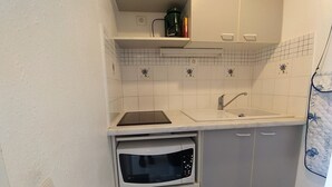 Ett kompakt kök med en inbyggd ugn, en diskho och en mikrovågsugn.