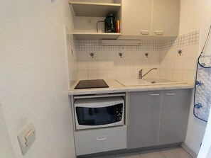 A compact kitchen with a built-in oven, a sink, and a microwave. - Apartment with pool, parking, lake view - 4 guests (Le Grau-du-Roi)