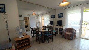 Ett vardagsrum med en matplats, en soffa, en fläkt och en tv.