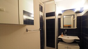 Un bany amb un lavabo blanc, un mirall i un espai de banyera.